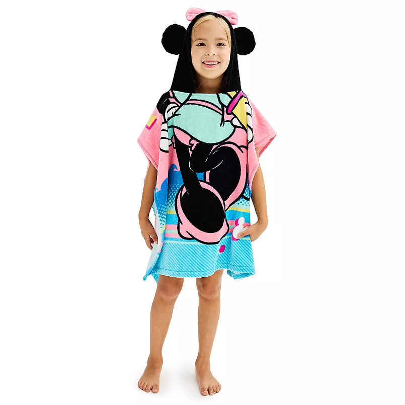 A young girl smiling while wearing a hooded towel with a Minnie Mouse design.