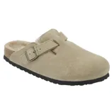 A tan suede clog-style slipper with a single adjustable strap and buckle; features a black rubber sole and shearling lining for comfort.