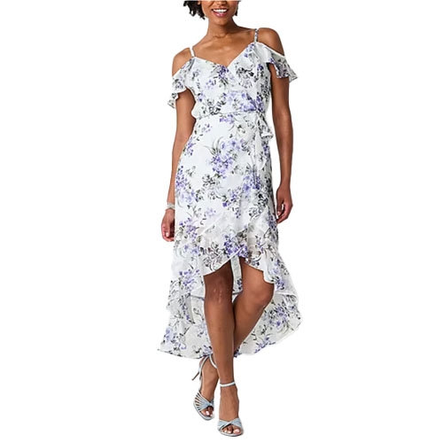 A woman is wearing a floral cold-shoulder dress with ruffled details and an asymmetrical hem, paired with strappy high-heel sandals.