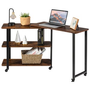 Hinged end table with a dark wood finish and black metal legs, featuring wheels for mobility. It includes three open shelves, a potted plant, a laptop, a lamp, books, decorative items, and a basket for storage.