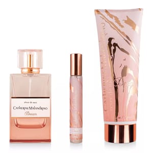A Catherine Malandrino Dream gift set featuring a bottle of perfume, a travel-size rollerball, and a tube of scented cream, all in pink and gold tones.
