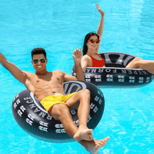 Two people floating on inflatable pool rings in clear blue water.