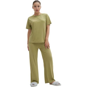 A person is wearing a comfy olive green pajama set with a short-sleeved top and long pants, paired with cozy gray slippers.