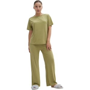 A person is wearing a comfy olive green pajama set with a short-sleeved top and long pants, paired with cozy gray slippers.