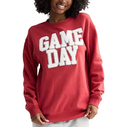 A person wears a red sweatshirt featuring the words \“GAME DAY\“ in large white letters.