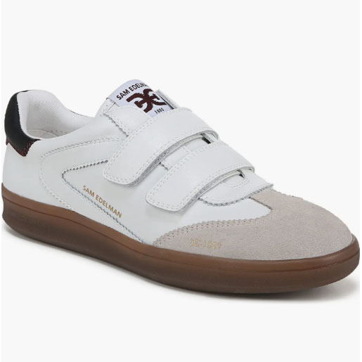 A white sneaker with two velcro straps, featuring a suede toe, a brown sole, and \“SAM EDELMAN\“ branding on the side.