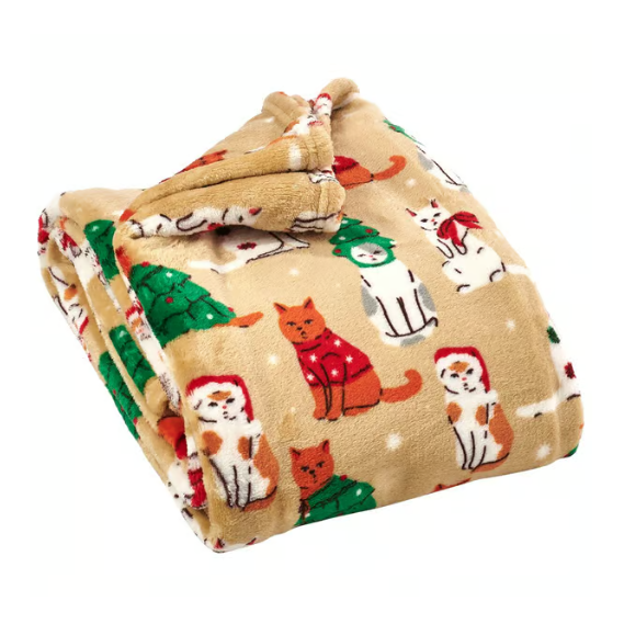 A plush blanket featuring a festive design with cats wearing Santa hats and Christmas trees on a beige background.