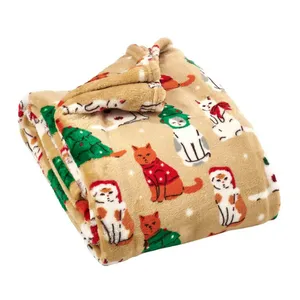A plush blanket featuring a festive design with cats wearing Santa hats and Christmas trees on a beige background.