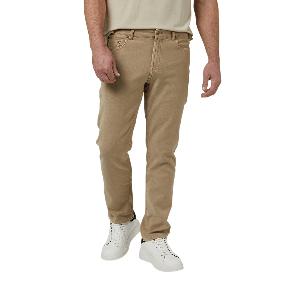 A person wears beige slim-fit jeans paired with white sneakers featuring black accents and a light-colored t-shirt.