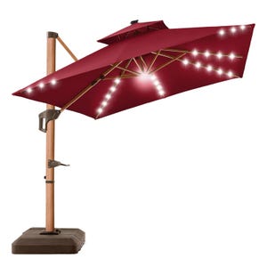 A red offset patio umbrella with integrated string lights, featuring a wooden pole and a crank system for opening and adjusting.