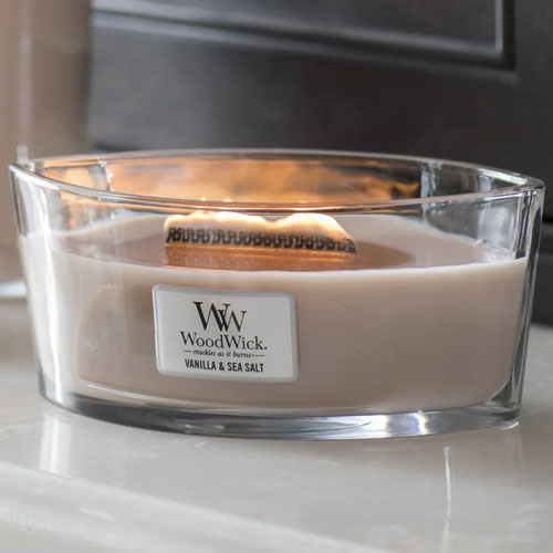 a tan woodwick candle on a white countertop
