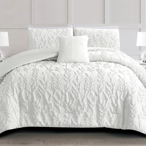A white quilted bedding set featuring a textured leaf pattern with matching pillows is shown. The bed is flanked by two table lamps, creating a clean and minimalist aesthetic.