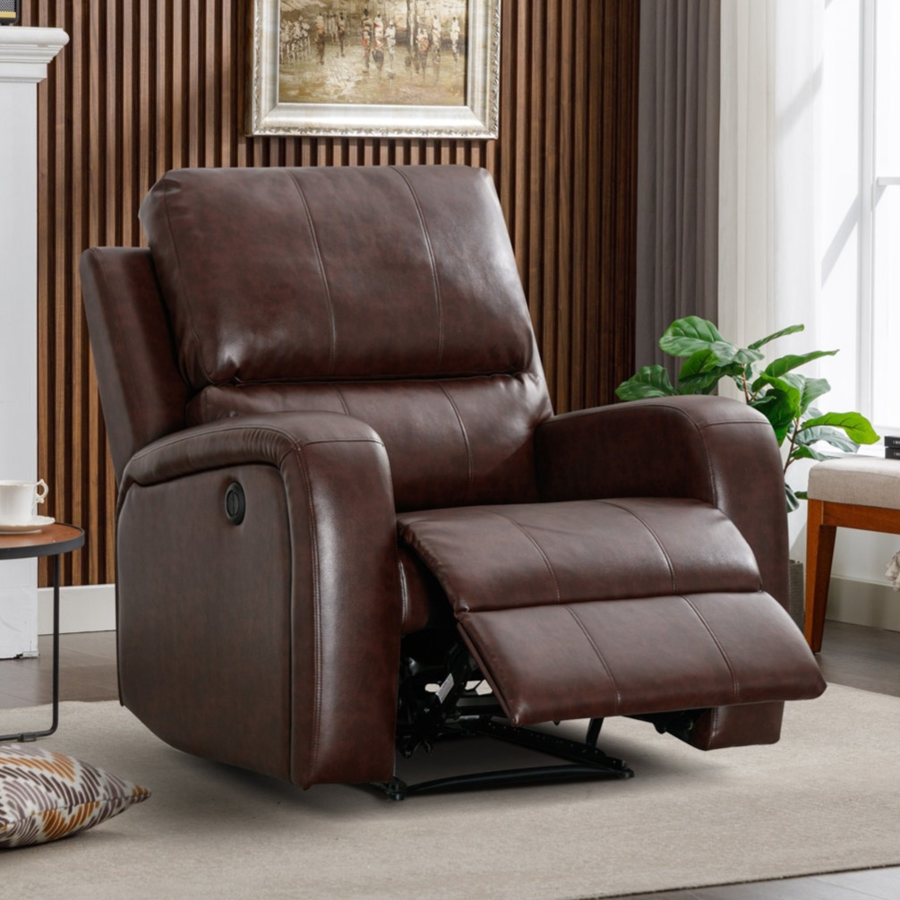A brown leather reclining chair with an extended footrest is positioned in a cozy living room next to a small table holding a teapot and cup. A decorative painting, a plant, and a cushioned floor complete the inviting setting.