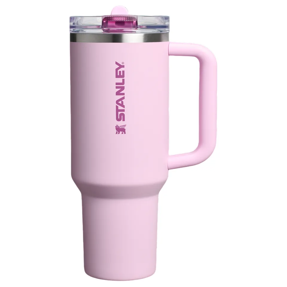 Pink Stanley tumbler with a handle, featuring a clear lid and bold branding on the side.