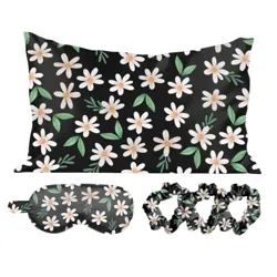 A black pillowcase, eye mask, and set of scrunchies featuring a white daisy and green leaf pattern.