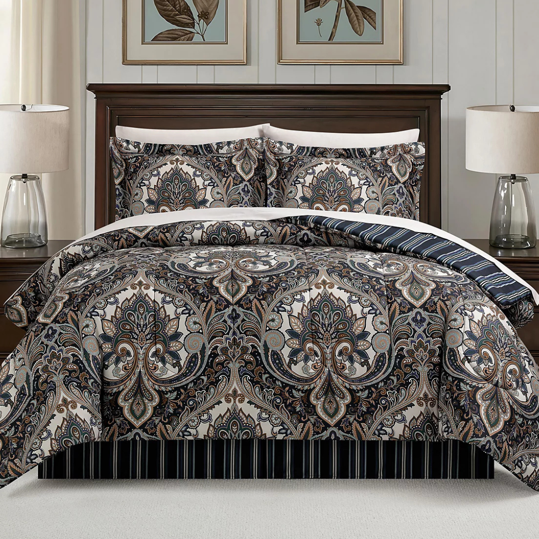 A bed set featuring a detailed paisley pattern with matching pillow shams, set against a dark wooden bed frame. Two table lamps with clear glass bases are on the nightstands beside the bed.