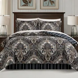 A bed set featuring a detailed paisley pattern with matching pillow shams, set against a dark wooden bed frame. Two table lamps with clear glass bases are on the nightstands beside the bed.