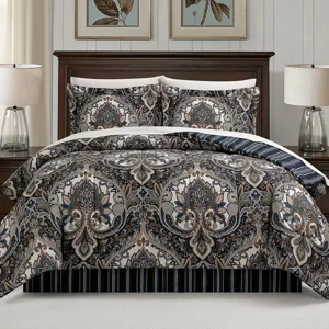 A bed set featuring a detailed paisley pattern with matching pillow shams, set against a dark wooden bed frame. Two table lamps with clear glass bases are on the nightstands beside the bed.