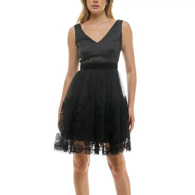 A sleeveless black dress with a V-neckline and fitted waist, featuring an embellished mesh skirt with lace detailing at the hem, creating a layered effect.