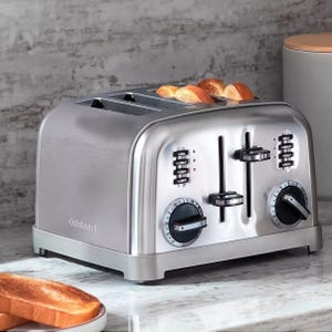 A stainless steel four-slice toaster with dual control panels and toast popping up.