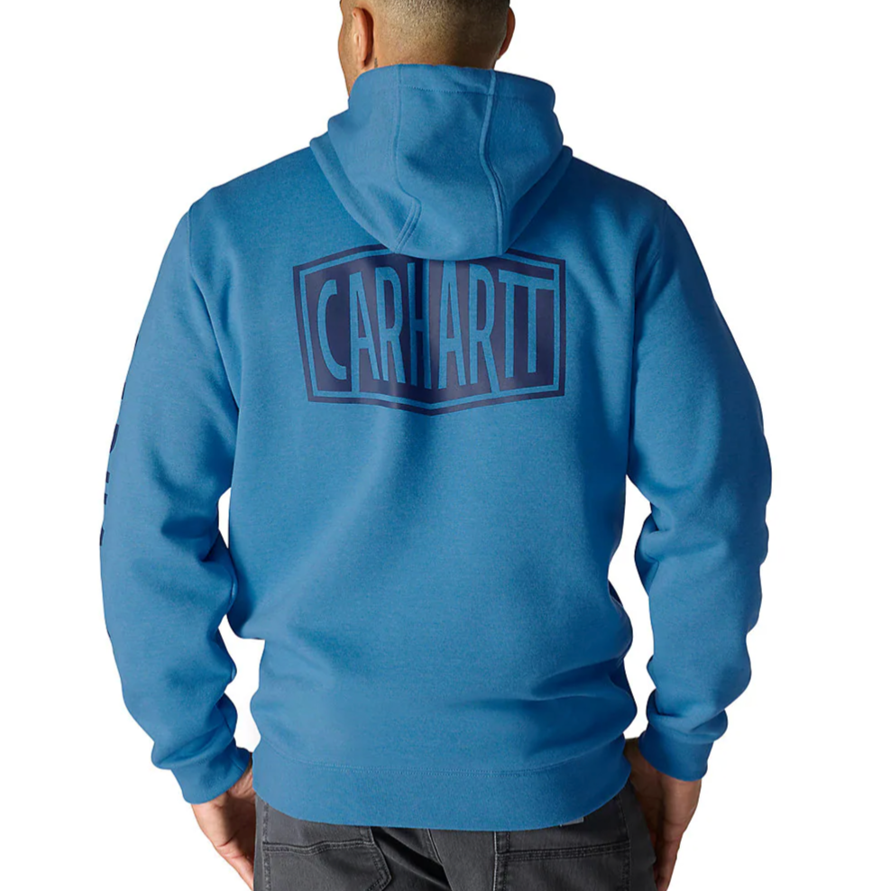 Blue Carhartt hoodie with a large logo on the back, worn by a person facing away, paired with dark pants.
