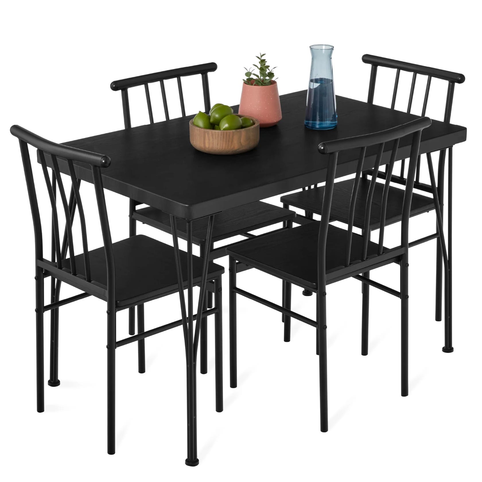 A black dining set with a rectangular table and four matching chairs features a minimalist design. Visible items include a bowl of green apples, a potted plant, and a blue carafe on the table.
