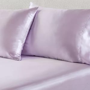 Light purple satin pillowcases and bed sheet.