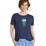 Woman wearing a navy blue T-shirt with a floral jar design and light blue pajama pants featuring a floral pattern and pink drawstring.