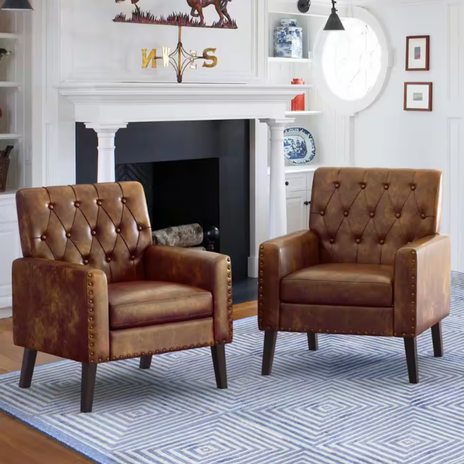 Two brown leather tufted accent chairs with nailhead trim and dark wooden legs, placed on a blue and white geometric-patterned rug.
