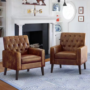 Two brown leather tufted accent chairs with nailhead trim and dark wooden legs, placed on a blue and white geometric-patterned rug.