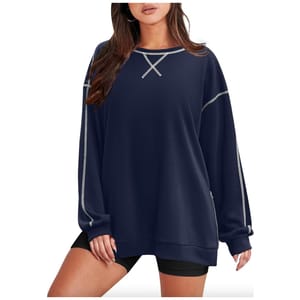 A woman is wearing an oversized navy blue sweatshirt with a lace-up neckline and side stripes.