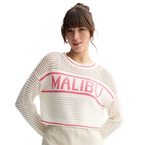 A woman wears a white open-stitch pullover with \“MALIBU\“ in pink lettering on the front. The sweater features a casual, beachy design with a relaxed fit and long sleeves.