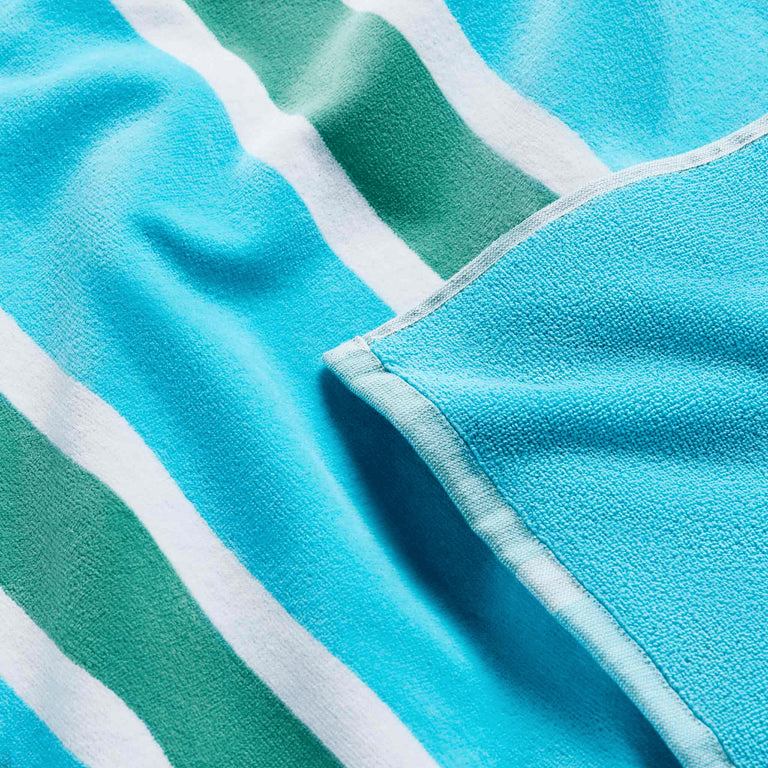A teal and white striped beach towel with a close-up view showing the texture and stitching details.