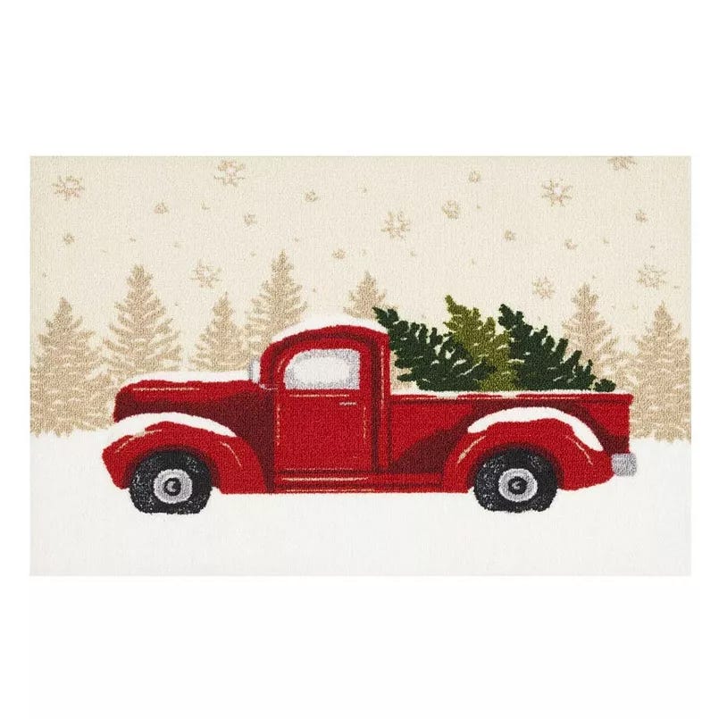 A festive rug featuring a red vintage truck carrying a green Christmas tree, set against a backdrop of beige trees and snowflakes.