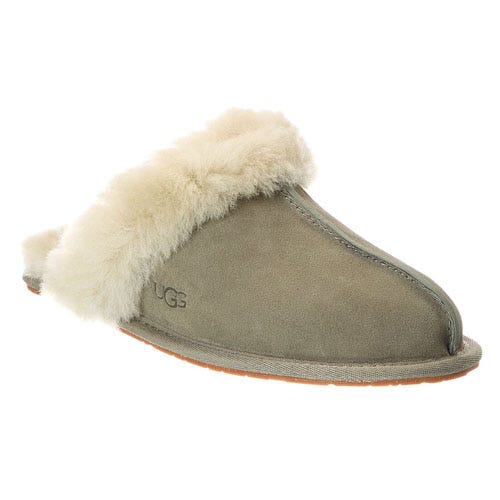 A suede slip-on slipper with a fluffy cream-colored lining, featuring a small logo on the side.