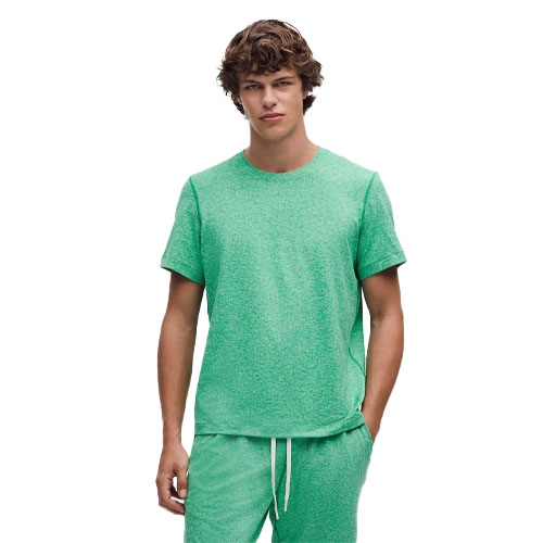 A person is wearing a green short-sleeve T-shirt paired with matching green drawstring shorts.