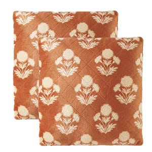 Two decorative orange cushions featuring a white floral pattern.