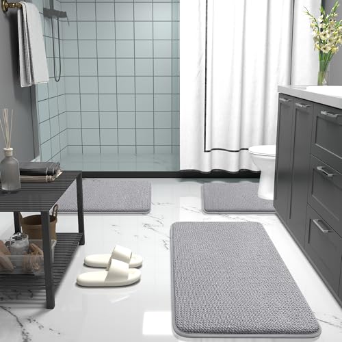 Bathroom setup with grey bath mats, a black storage shelf, white slippers, grey cabinets, and decorative flowers next to a shower area with a white curtain and tiled walls.