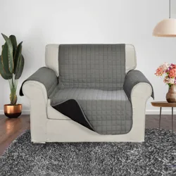 Armchair with a gray quilted cover, sitting on a gray shag rug. Nearby are a potted plant, a small table with flowers, and a hanging lamp.