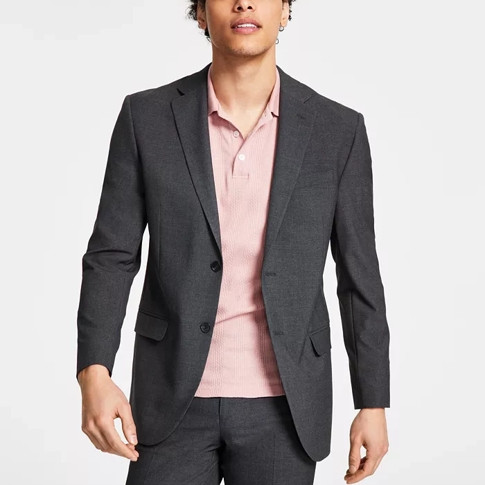 A man is wearing a dark gray suit with a light pink button-up shirt.