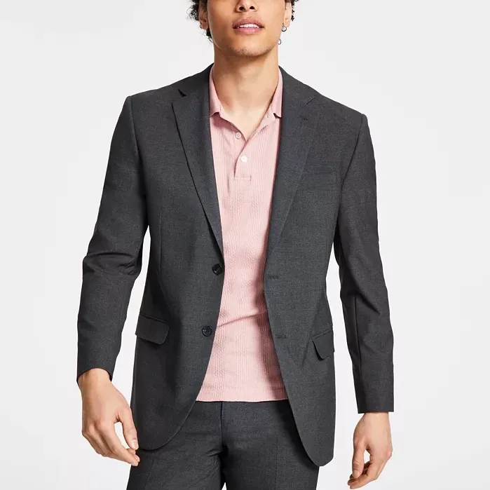 A man is wearing a dark gray suit with a light pink button-up shirt.