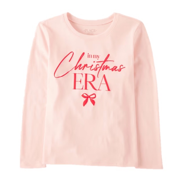 A long-sleeve pink shirt with red text that says \“in my Christmas ERA\“ along with a small red bow graphic below the text.