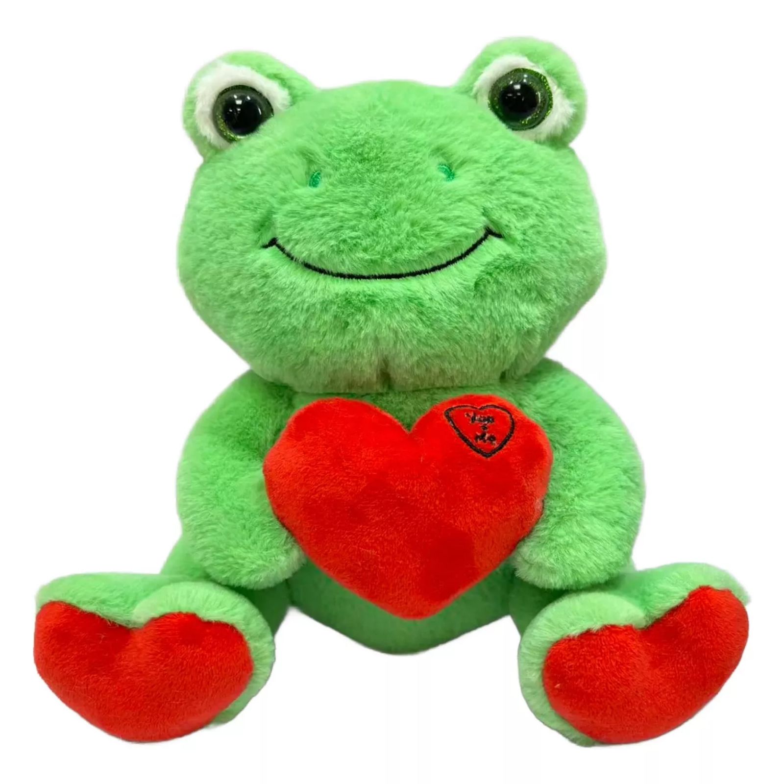 A plush green frog with a smile is holding a red heart. The heart has \“You & Me\“ written on it.