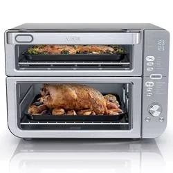 Ninja DoubleStack XL Oven is a countertop appliance with two cooking compartments, allowing for simultaneous baking and roasting. It features digital controls and a stainless steel finish, shown roasting a chicken and vegetables on the bottom and baking on the top.