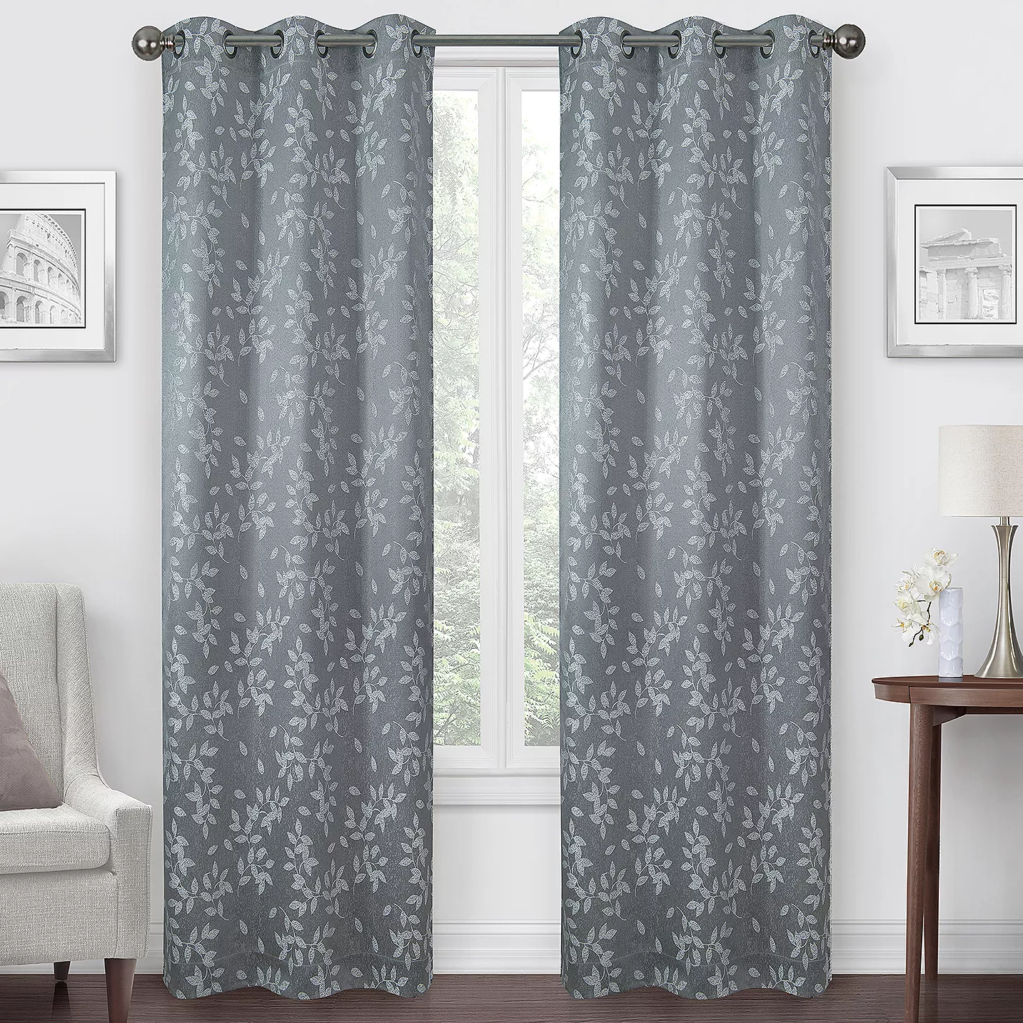 A pair of gray curtains with a leaf pattern hanging on a window.