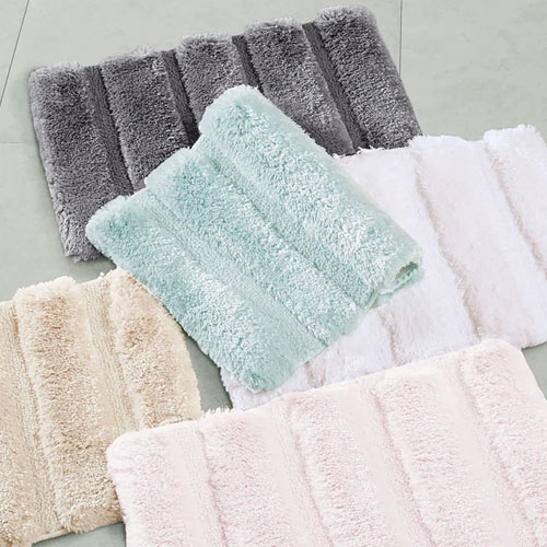 a collection of bath mats in light blue, grey, white, and beige