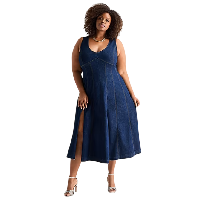 A woman is wearing a sleeveless, deep blue denim midi dress with a V-neckline and side slit, paired with silver strappy high-heeled sandals and a gold necklace.