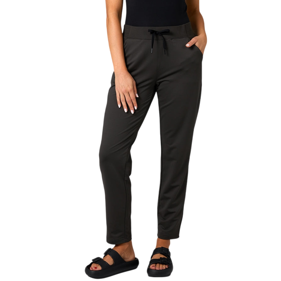 A person is wearing black drawstring pants paired with black sandals featuring buckles, posed against a neutral gray background.