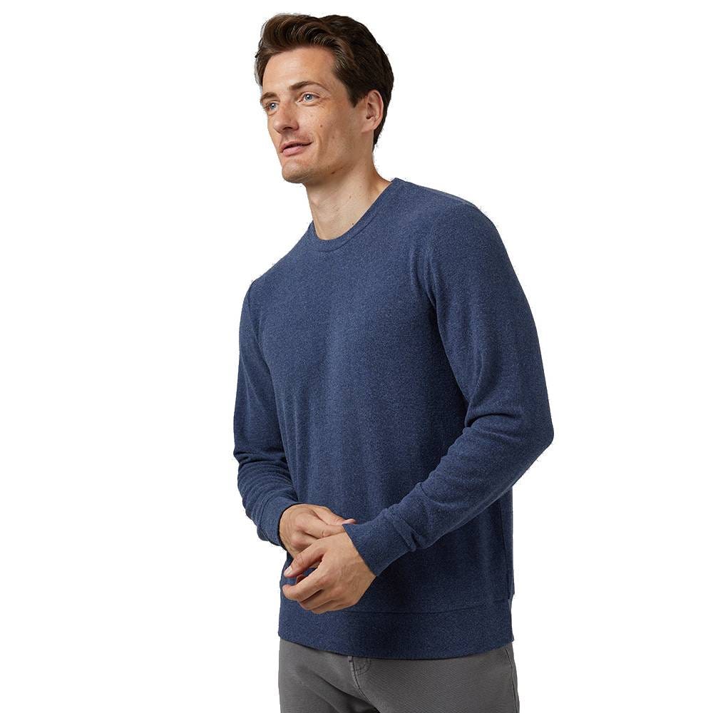 A man is wearing a blue crew-neck sweater and gray pants.