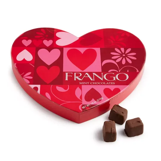 Heart-shaped box of Frango Mint Chocolates with a red and pink design featuring hearts and flowers, accompanied by three chocolate pieces.